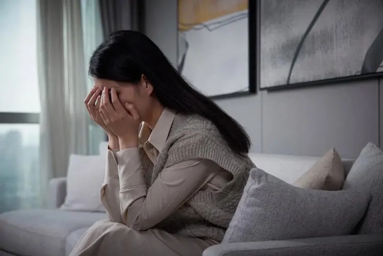 She covered her face with her hands in the living room because of stress