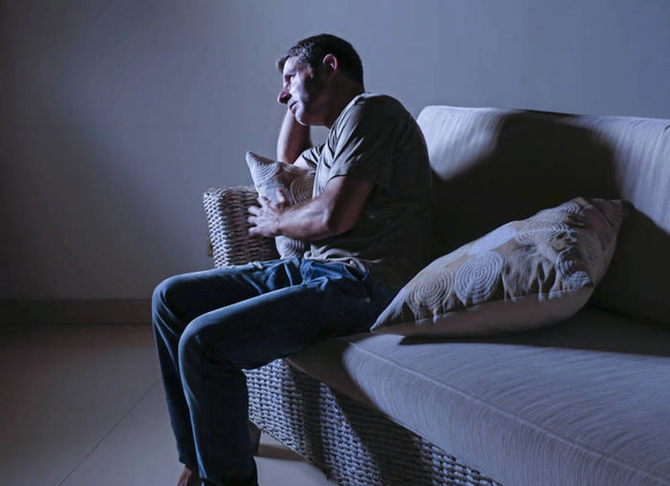 Desperate sad and depressed man is sad on the sofa at home