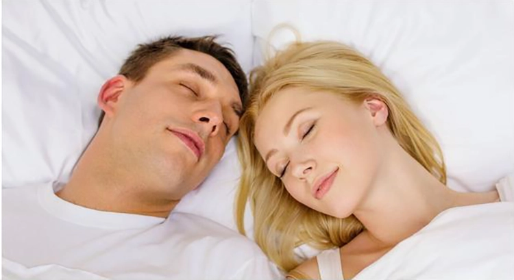 A couple falls asleep happily in bed.