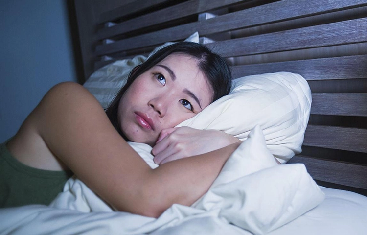 Young and beautiful Asian woman lying in bed with insomnia