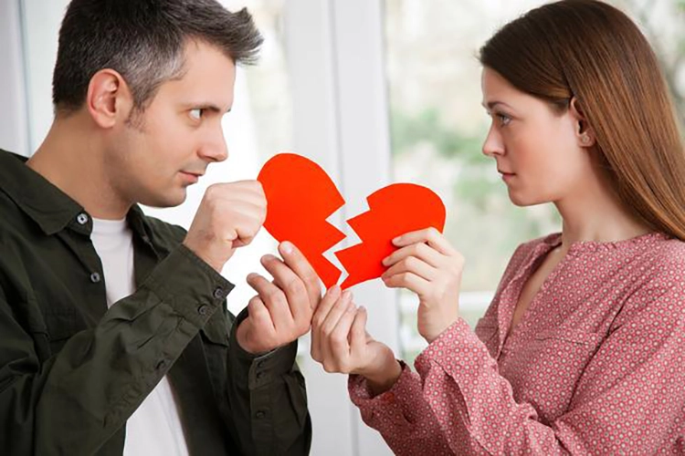 Two people in love tear the red love heart in their hands into two halves.