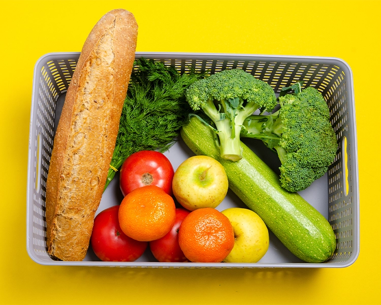 A basket of bread, vegetables and fruits.