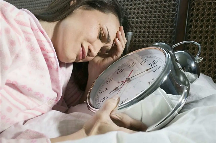 She was holding a huge alarm clock on the bed with a face full of anxiety.