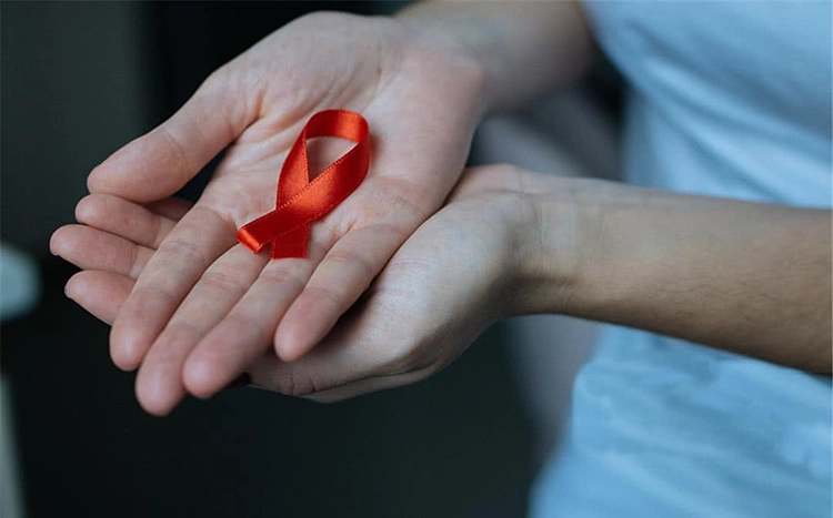 Holding the red string of the AIDS Association in his hand.