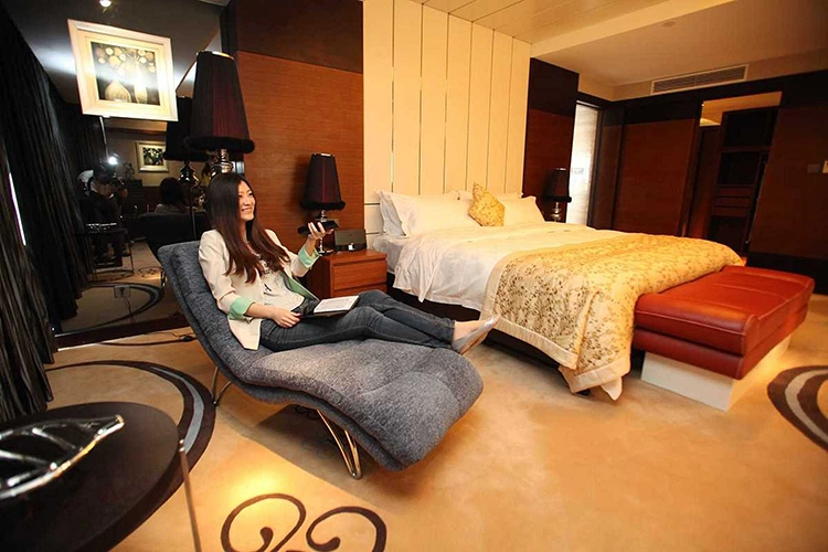 An Asian woman happily watches TV in a high-end presidential suite.