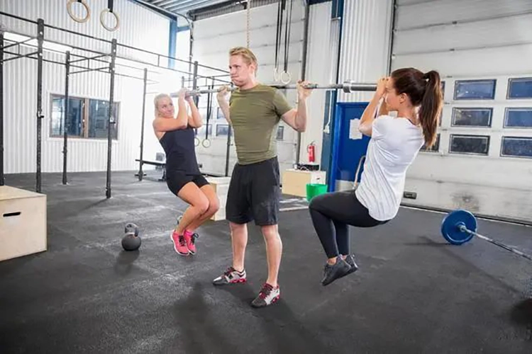 Un homme et deux femmes font des squats avec mise en charge