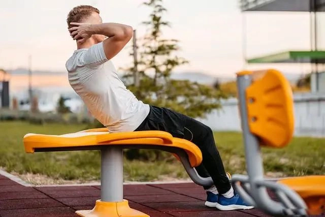 Il fait des exercices abdominaux dans le parc